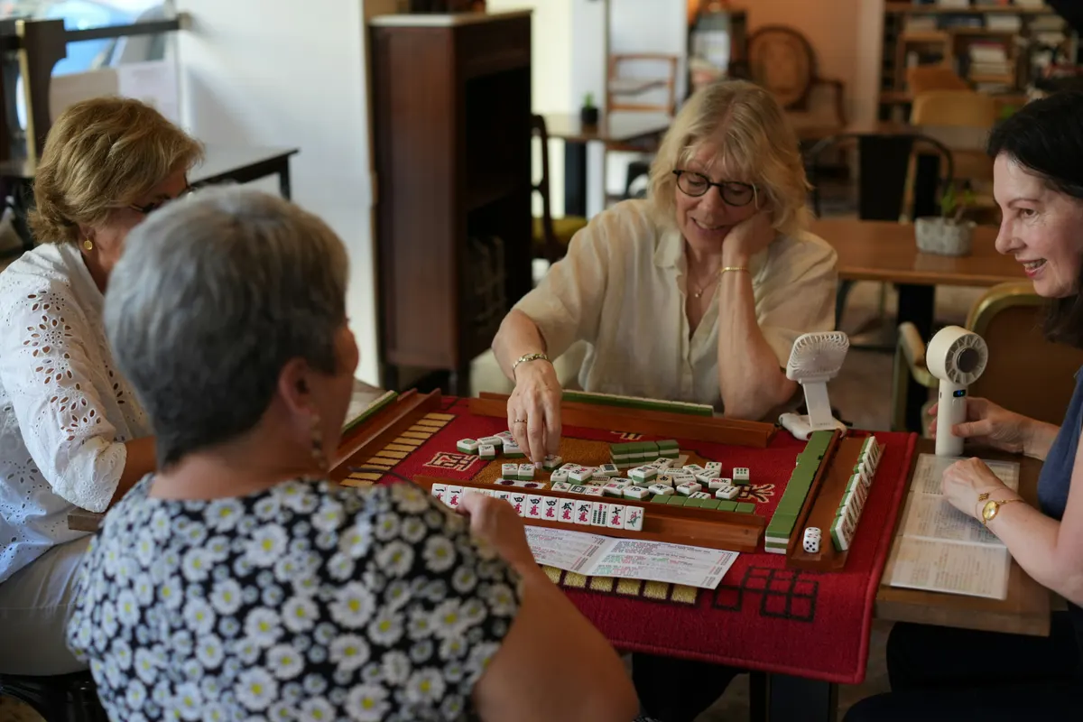 Four friends gathered around a table playing a game of American Mahjong together