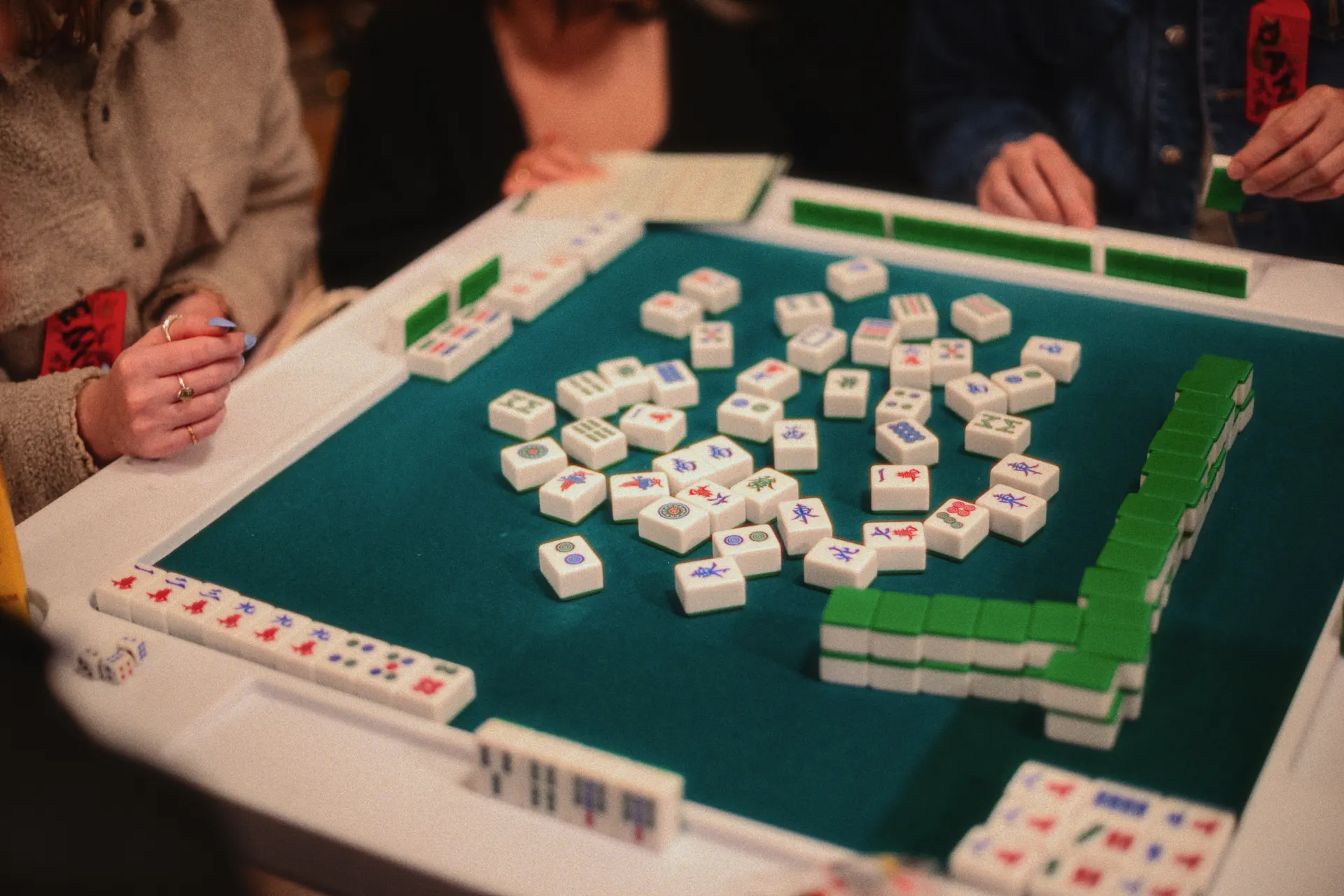 A group of people gathered around a table playing a game of mahjong together