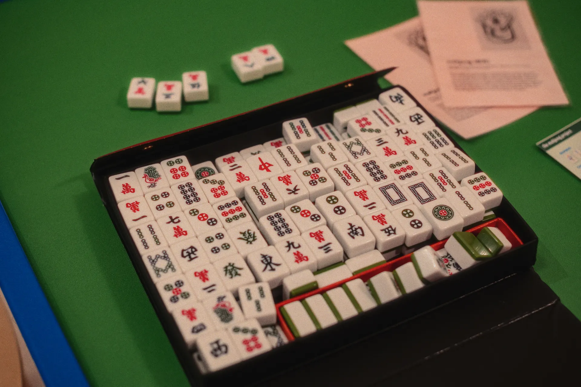 A full set of American Mahjong tiles arranged face-up on a green playing surface