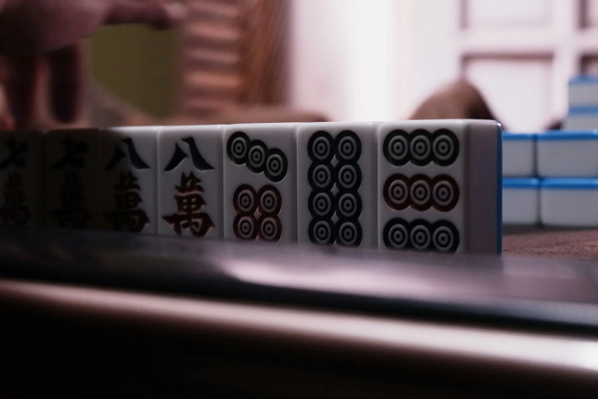 Mahjong tiles stacked in neat rows on a dark honeycomb playing surface